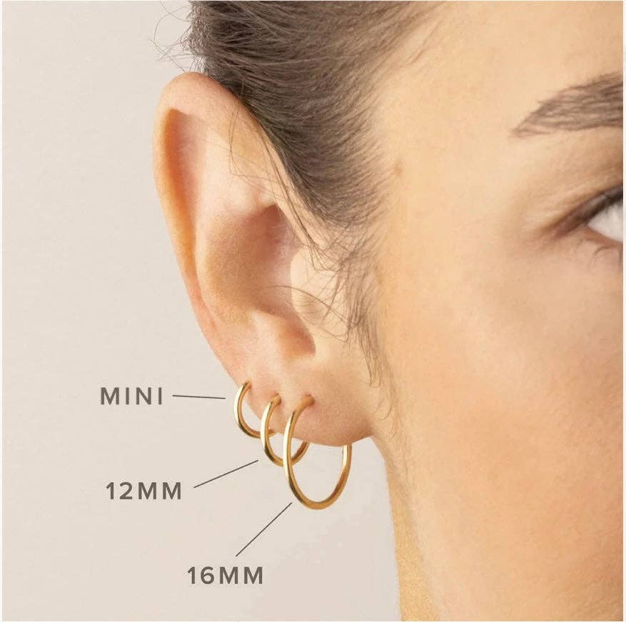 Close-up of a model wearing three different sizes of gold hoop earrings, labeled Mini, 12mm, and 16mm to show size comparison.