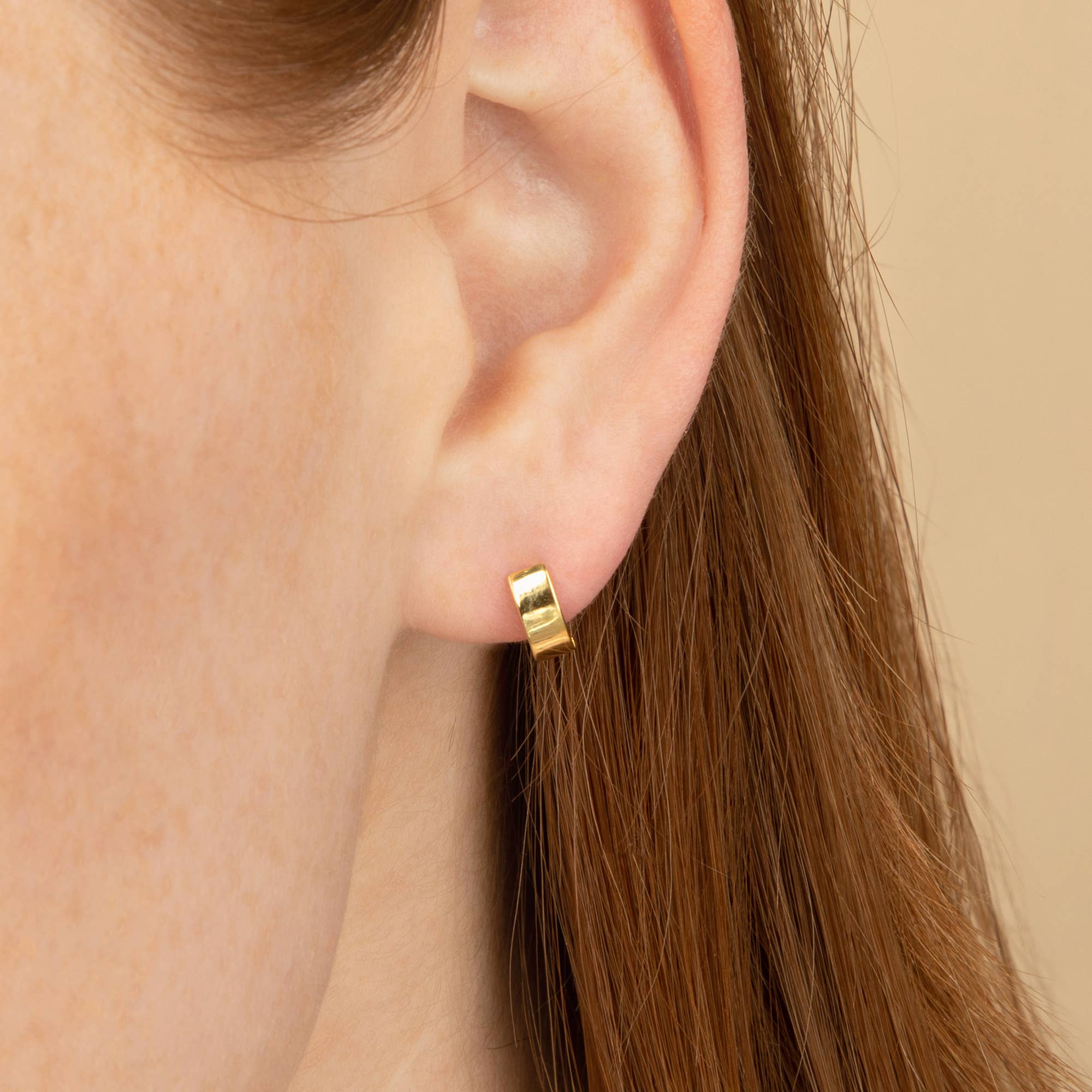 Minimalist gold huggie hoop earrings worn by a model
