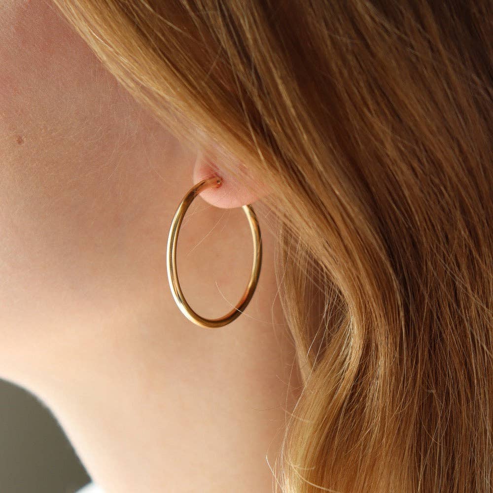 Gold hoop earrings worn by a model, showcasing their elegant design