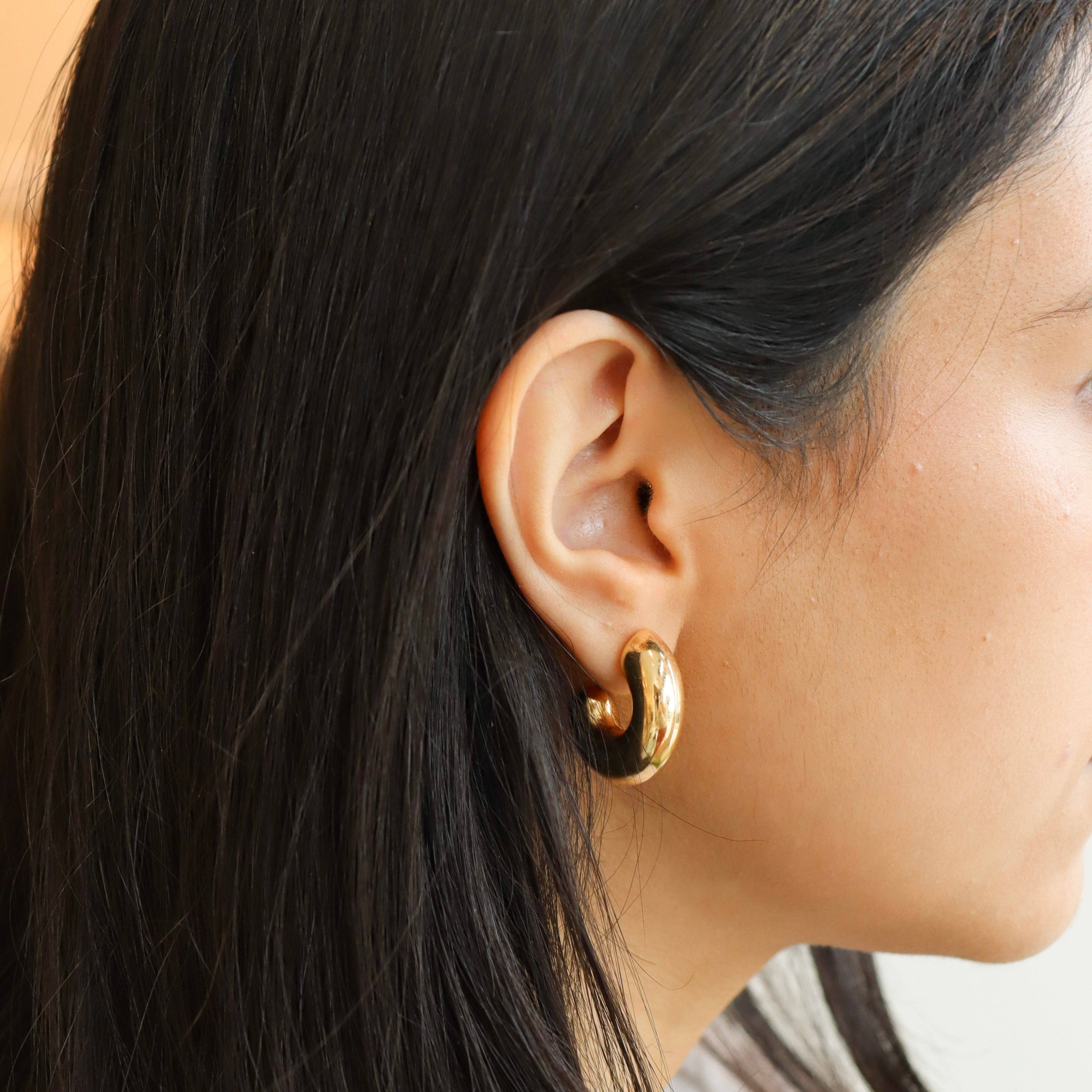 Chunky gold hoop earrings worn by a model, highlighting their bold design