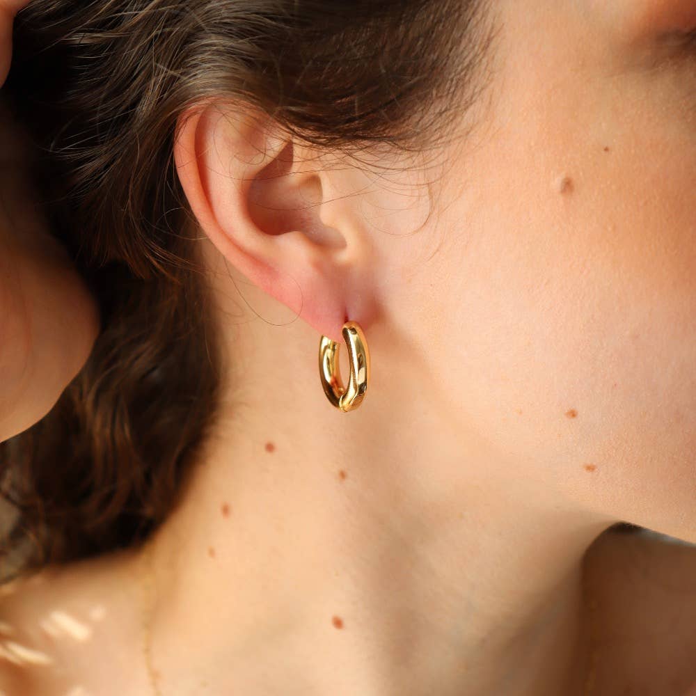 Chunky gold huggie hoop earrings worn by a model, showcasing their elegant design