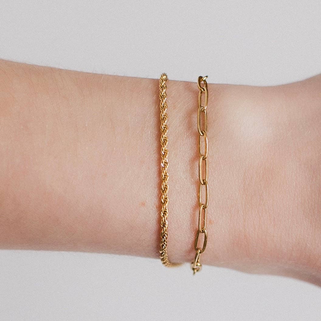 Delicate gold chain link bracelet paired with a twisted gold bracelet on a model's wrist