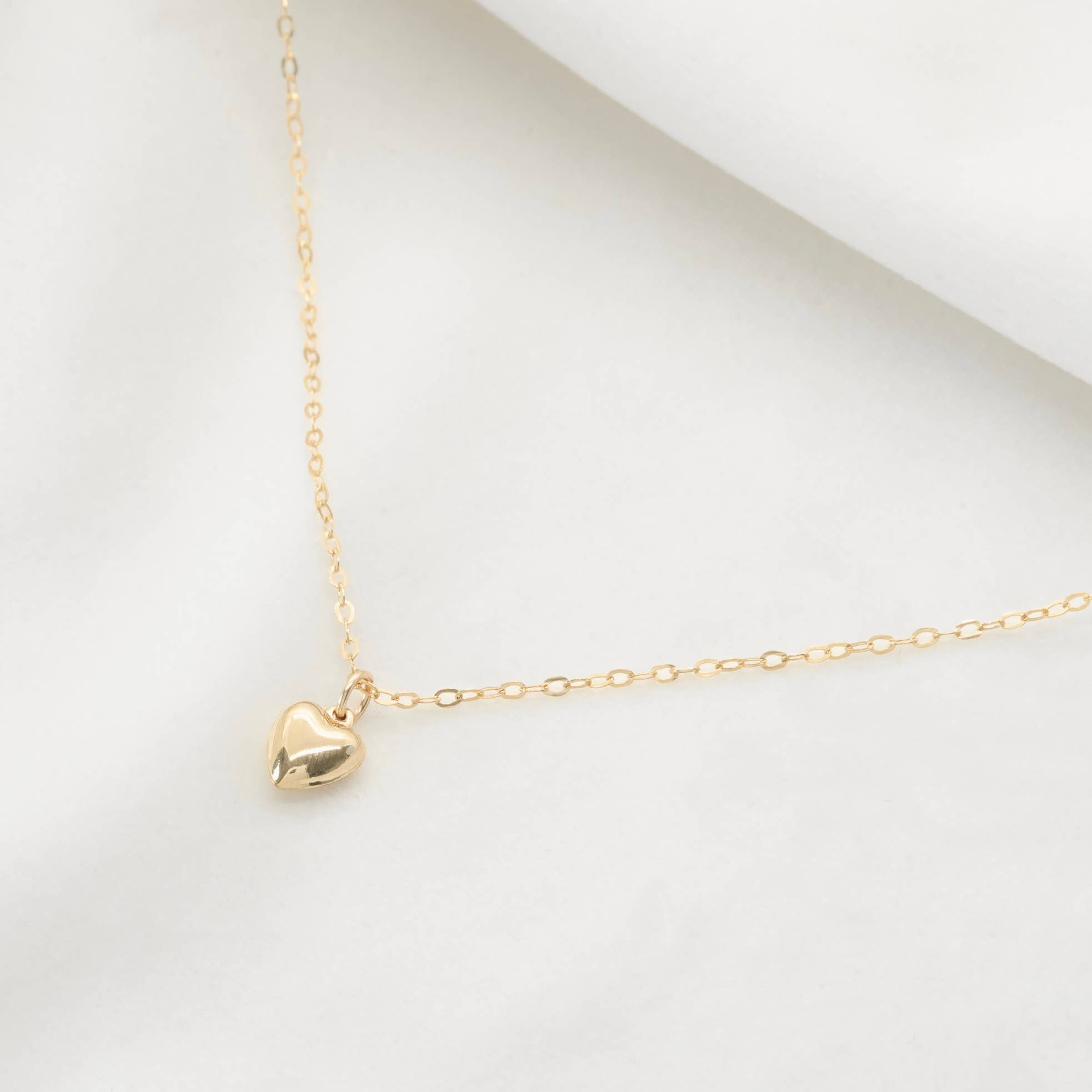 Gold Cara Necklace with a heart pendant on a white background