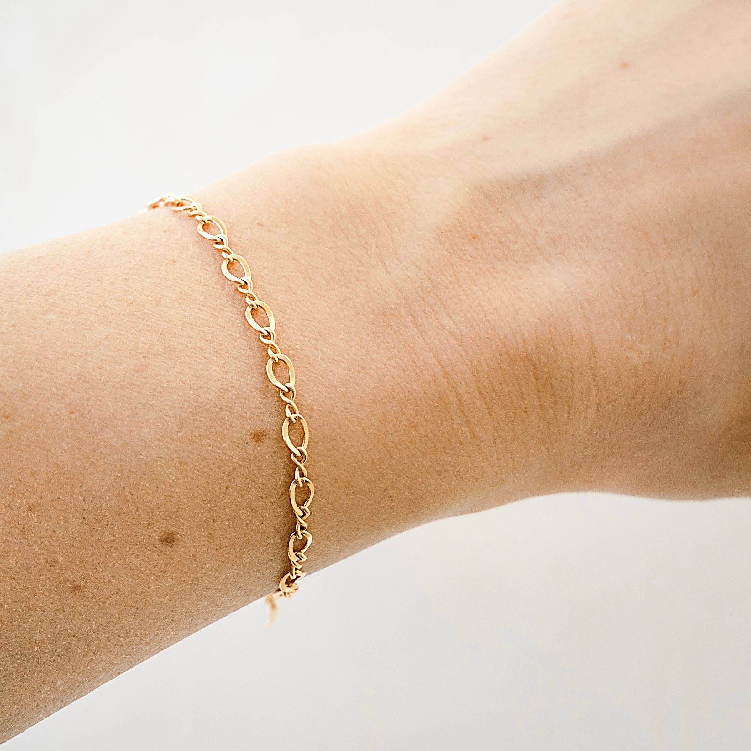 Gold chain bracelet with oval links shown on a wrist, highlighting the minimal and elegant design for a lightweight and comfortable fit.