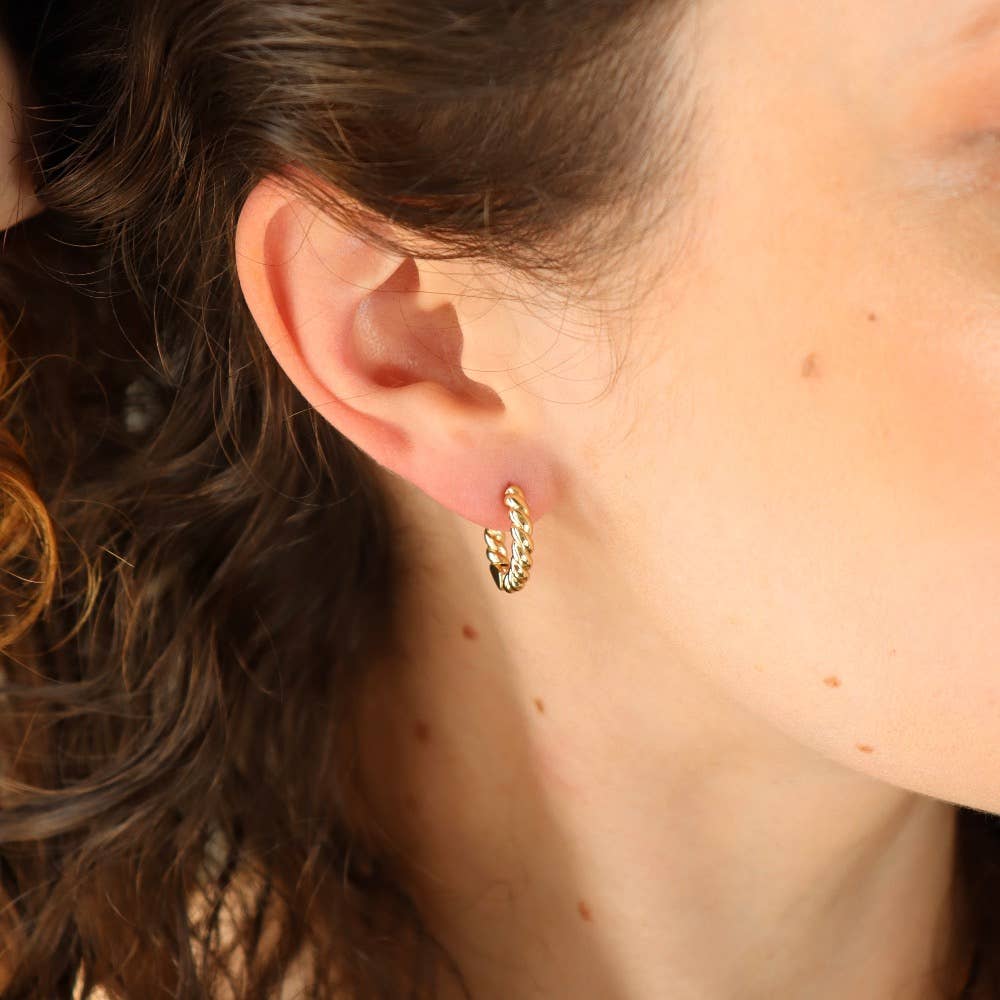 Gold croissant hoop earrings worn by a model, showcasing their intricate design